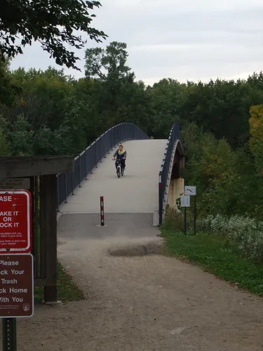 Photo of a person biking over a pedestrian path with a forest in the background